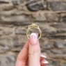 hand holding 3 stone halo engagement ring vr1066 in yellow gold