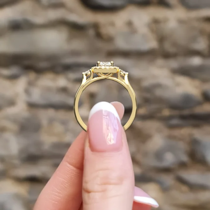 hand holding 3 stone halo engagement ring vr1066 in yellow gold