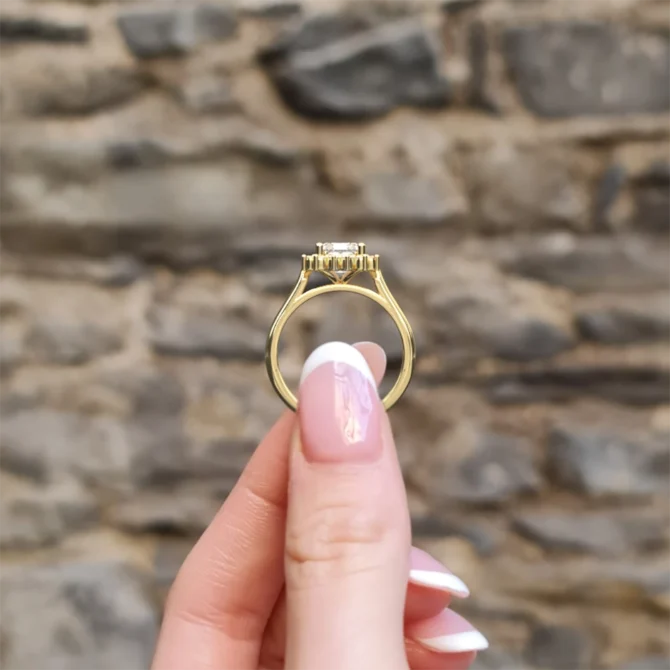 hand holding emerald cut halo engagement ring vr1105 sb7191 in yellow gold