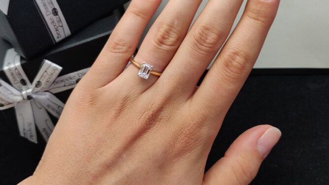 yellow-gold-emerald-cut-diamond-solitaire-engagement-ring-on-hand-sr1045-image-1