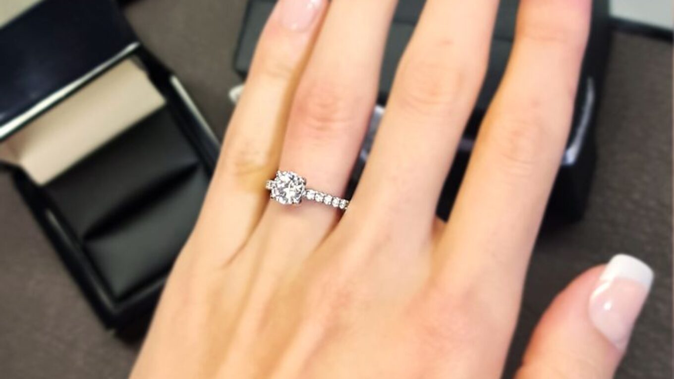 pr1013-round-cut-diamond-side-stone-engagement-ring-on-hand-image-1