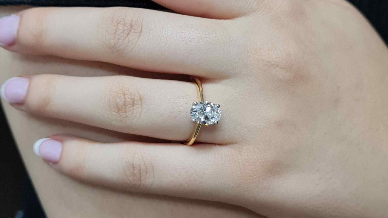 Oval solitaire diamond ring on finger at 1.0ct in yellow gold